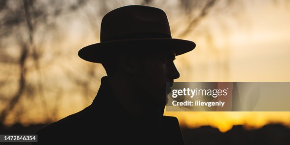 Male portrait. Brunet man in hat and coat in forest. Noir detective