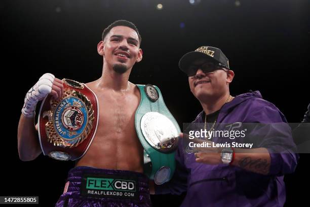 Diego Pacheco poses for a photograph with their coach after defeating Jack Cullen during the WBO International Super Middle Title fight between Diego...