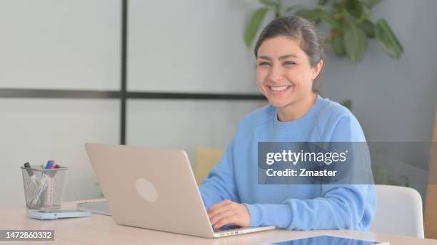 Indian Woman Smiling at Camera while using Laptop indian woman smiling at camera while
