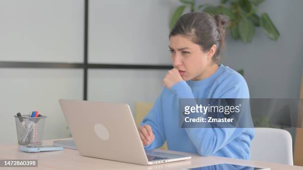 indian woman coughing while working laptop