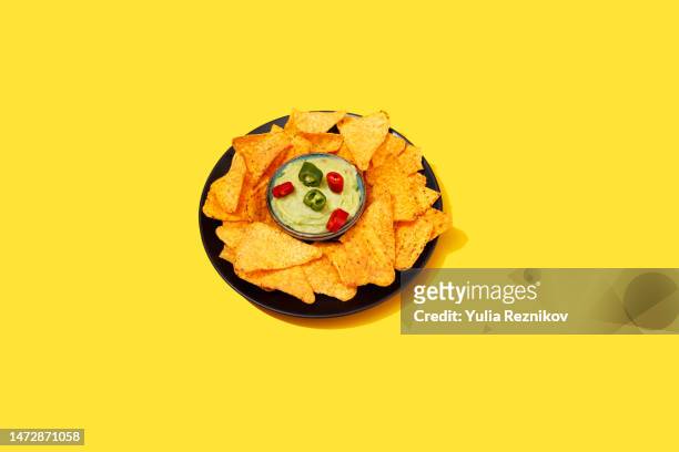 tortilla chips with guacamole and chili pepper on the yellow background- vegan food - bowl of chili stock-fotos und bilder
