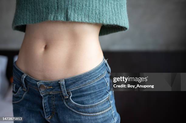 close up of woman with slim waist. conceptual shot of woman showing her diet results. - naveltruitje stockfoto's en -beelden