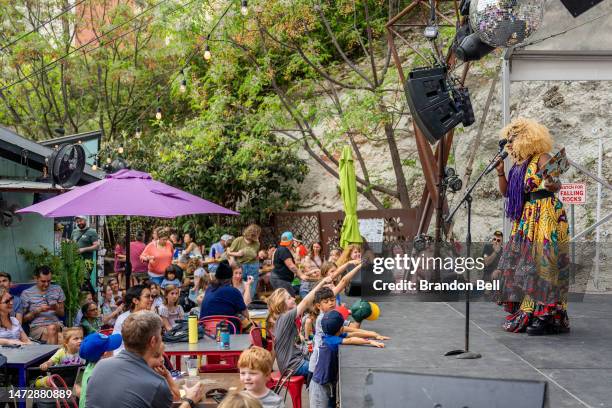 Drag Queen Beatrice Thomas, also known as Black Benatar, reads a book during a story time reading at the Cheer Up Charlies dive bar on March 11, 2023...