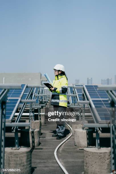 asian woman engineer is planning solar power plant on factory roof - hochspannungstransformator stock-fotos und bilder