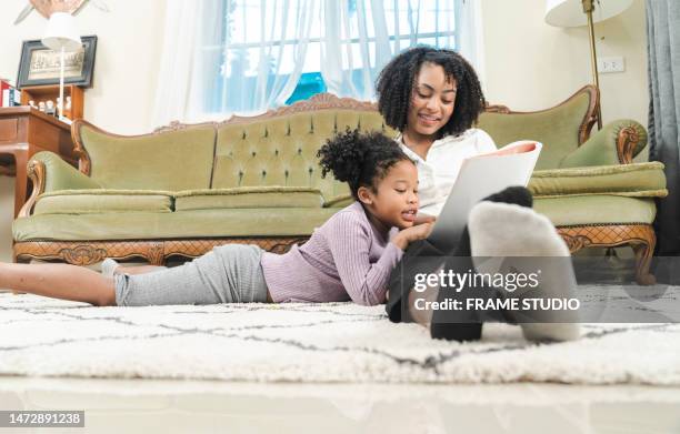 a young woman of african descent and her daughter are playing and telling stories to her daughter in the living room - story telling in the workplace stock pictures, royalty-free photos & images