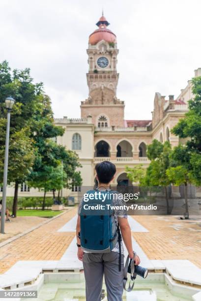 rear view of a tourist standing at sultan abdul samad building - malaysia kuala lumpur merdeka square stock pictures, royalty-free photos & images