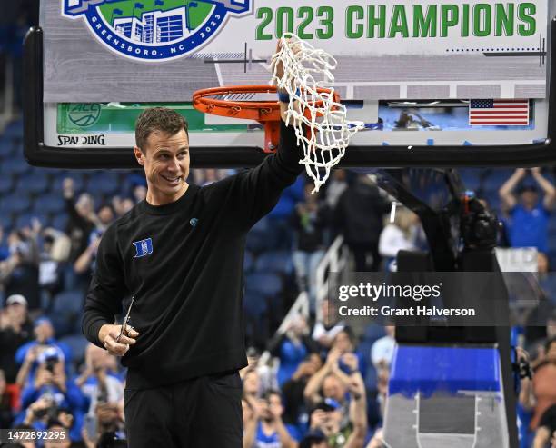 Head coach Jon Scheyer of the Duke Blue Devils cuts down the net after a win against the Virginia Cavaliers in the ACC Basketball Tournament...