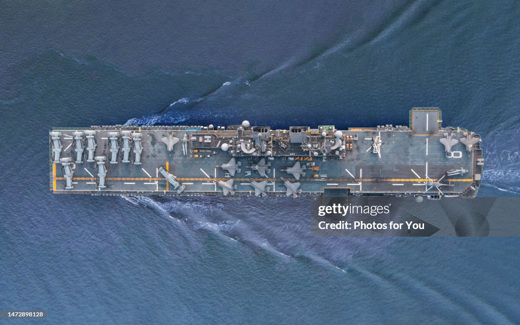 Aerial view/A fighter aircraft carrier sailing in the middle of the sea.