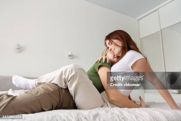 lesbian teen girlfriends cuddling in bed in bedroom - teen lesbian stockfoto's en -beelden