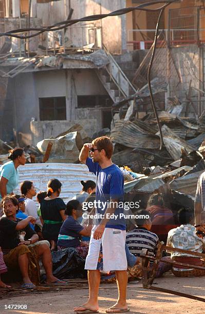 An unidentified tourist walks past rubble as Balinese pray near the bomb blast site October 13, 2002 in Denpasar Bali, Indonesia. The blast occurred...