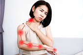 Asian woman suffering from nerve and muscle pain in neck and shoulder radiating down the arm