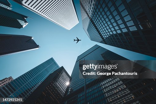 Airplane flying over tall skyscrapers