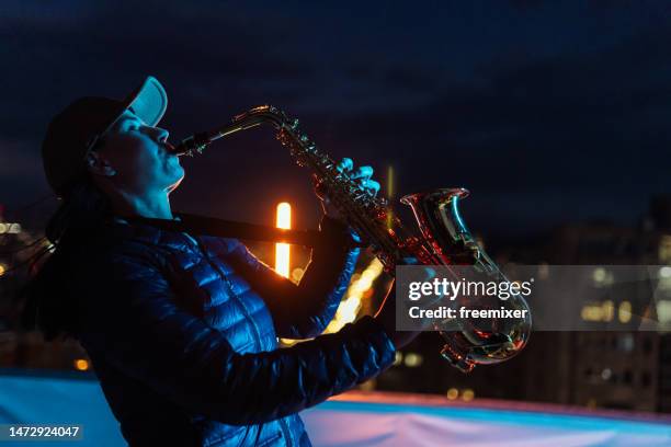 jazz saxophone female player on rooftop at night - woodwind instrument stock pictures, royalty-free photos & images