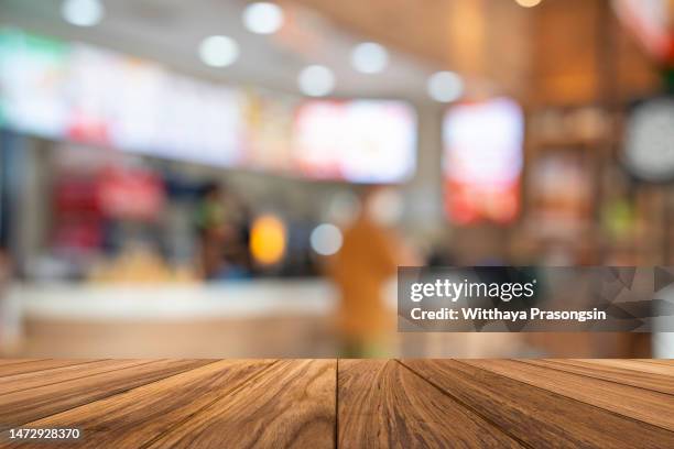 empty wooden table with fast food restaurant - blurred motion restaurant stock-fotos und bilder