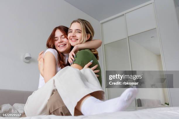 cheerful girl friends having fun on the bed in the bedroom - teen friendship - teen lesbian stockfoto's en -beelden