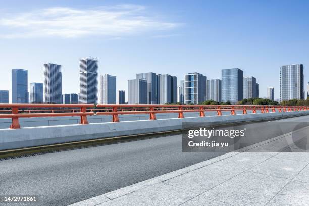 the road by the lake, the tall buildings in the financial district in the distance. wuxi city, jiangsu province, china. - curtain wall facade stock pictures, royalty-free photos & images