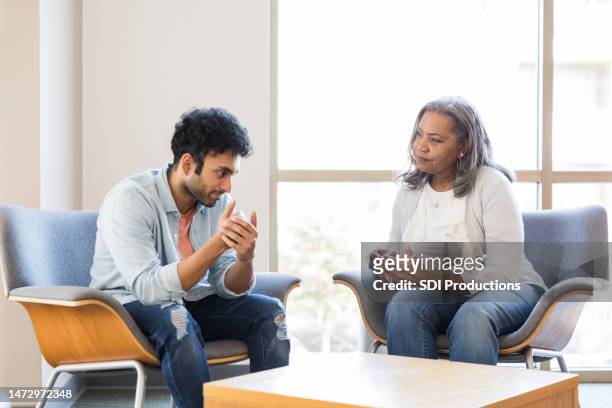 gestos masculinos adultos jóvenes mientras habla con su terapeuta de salud mental - alternative therapy fotografías e imágenes de stock