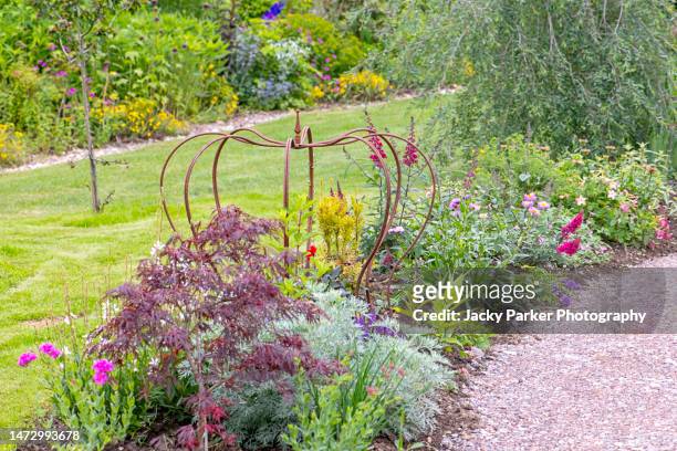 crown shaped wrought iron plant support in an english cottage garden flower border - garden feature stock pictures, royalty-free photos & images