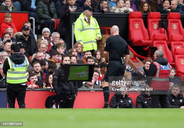 Referee Anthony Taylor checks the VAR screen before showing a red card to Casemiro of Manchester United during the Premier League match between...