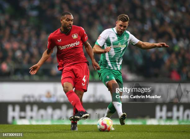 Jonathan Tah of Bayer 04 Leverkusen passes the ball whilst under pressure from Niclas Fuellkrug of SV Werder Bremen during the Bundesliga match...