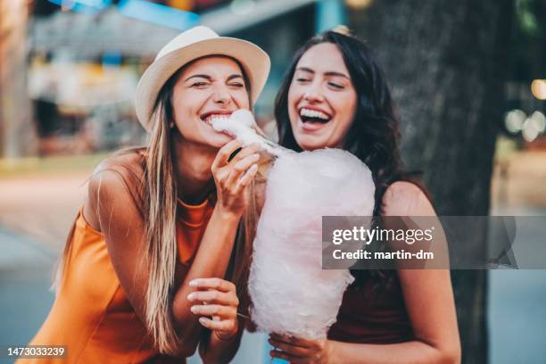 mujeres felices en el parque de atracciones - algodón de azúcar fotografías e imágenes de stock