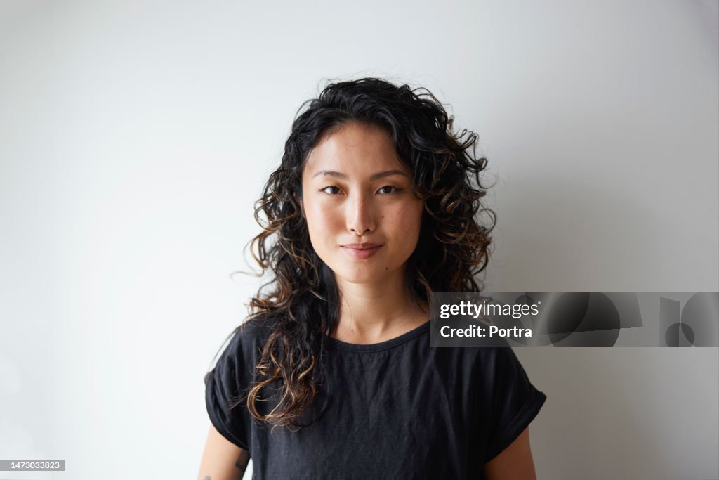 Portrait of attractive young asian woman agasint white wall
