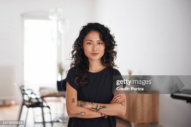 portrait of a beautiful young asian woman standing in living room - tattoo woman stock pictures, royalty-free photos & images