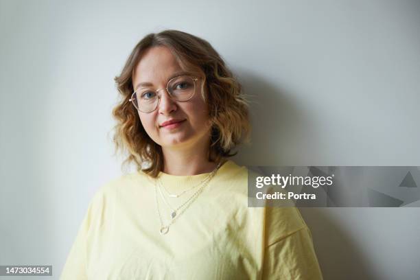 portrait of pretty young woman standing agasint white wall - lady 30s wearing glasses stock pictures, royalty-free photos & images