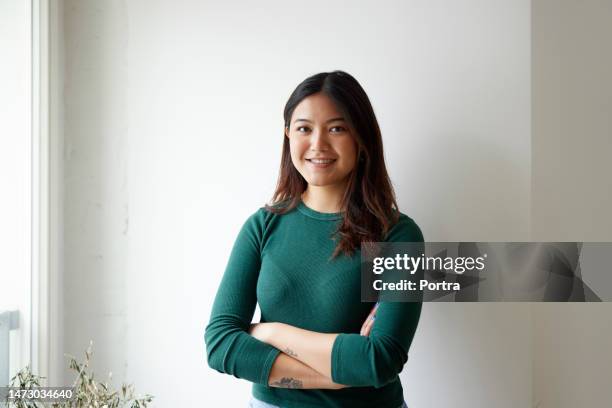 portrait of confident young asian woman standing by white wall - beautiful filipina woman stock pictures, royalty-free photos & images