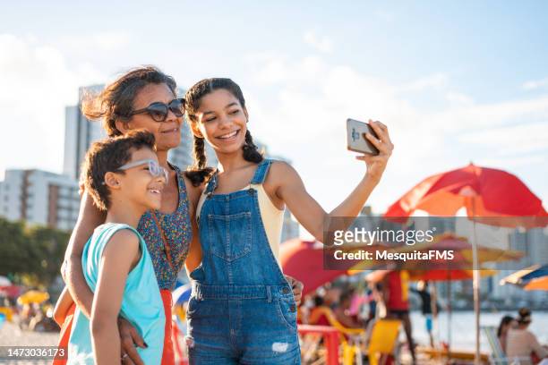 familie macht ein selfie am tropischen strand - hispanic man on beach stock-fotos und bilder
