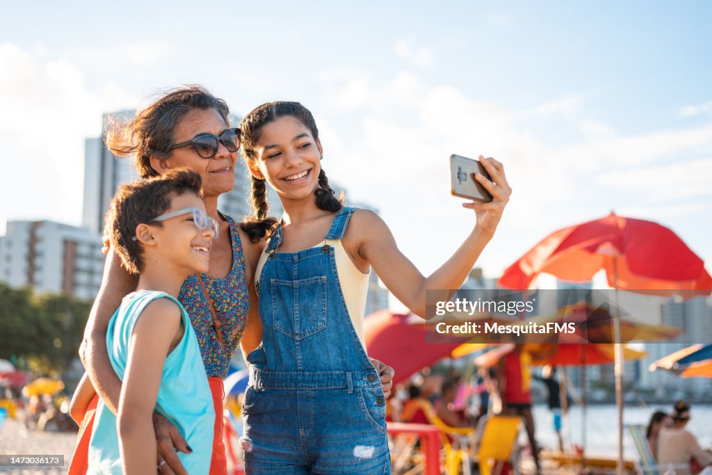 Família tirando uma selfie na praia tropical