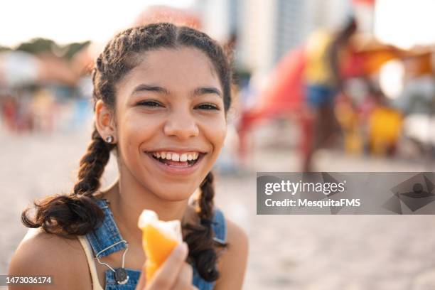 portrait of teen girl eating popsicle outdoors - icecream beach stock pictures, royalty-free photos & images