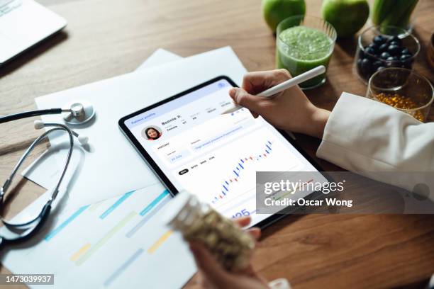 close-up of an unrecognizable medical practitioner analysing patient’s health records on digital tablet - electronic medical record stockfoto's en -beelden