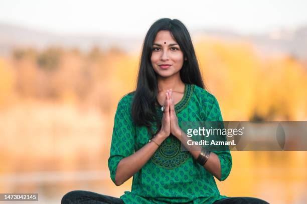 beautiful young asian indian woman with a bindi sitting and praying - new age stock pictures, royalty-free photos & images