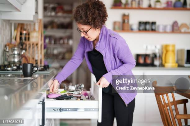 femme prenant des ustensiles de cuisine de l’armoire - placard photos et images de collection