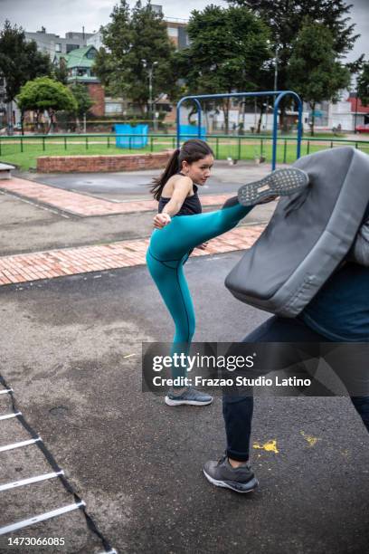 young woman doing a fight training with help of the her coach outdoors - self defence stock pictures, royalty-free photos & images
