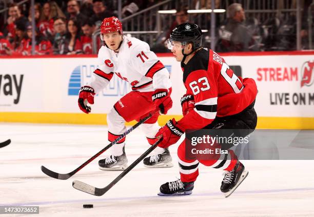 Jesper Bratt of the New Jersey Devils takes the puck as Jesper Fast of the Carolina Hurricanes defends during the first period at Prudential Center...