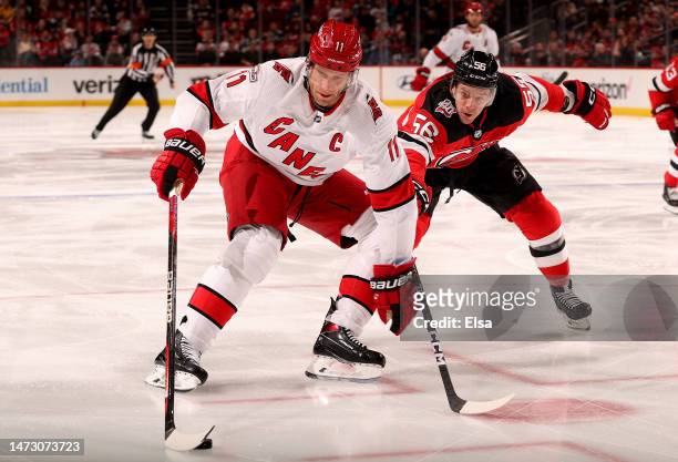 Jordan Staal of the Carolina Hurricanes takes the puck as Erik Haula of the New Jersey Devils defends during the first period at Prudential Center on...