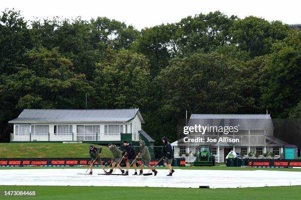 Grounds staff remove water from the covers during day five of the First Test match in the series between New Zealand and Sri Lanka at Hagley Oval on...