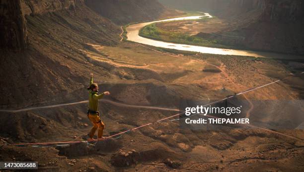 slack-lining hundreds of feet over canyon in moab park, utah - slackline stockfoto's en -beelden