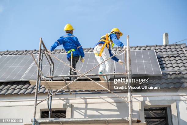 team engineers are installing solar photovoltaic panel system on roof of modern house. - solar system stock-fotos und bilder