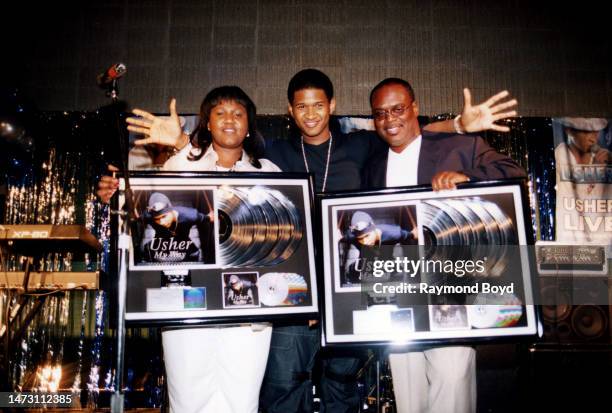 Singer Usher poses for photos with his mother Jonetta Patton and Antonio 'L.A.' Reid after receiving plaques to commemorate five million album sales...