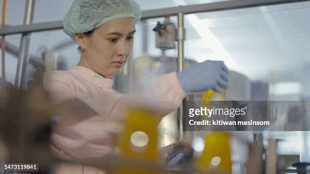 female nutritionist or quality control officer wear sterile clothing to prevent contamination,  check production and product quality of juice filling machine in production line at manufacturing plant. employee work in bottled fruit juice factory. - food contamination stock pictures, royalty-free photos & images