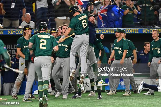 Robbie Glendinning and Aaron Whitefield of Australia celebrate with teammates after scoring runs by the two-run double of Logan Wade to make it 3-1...