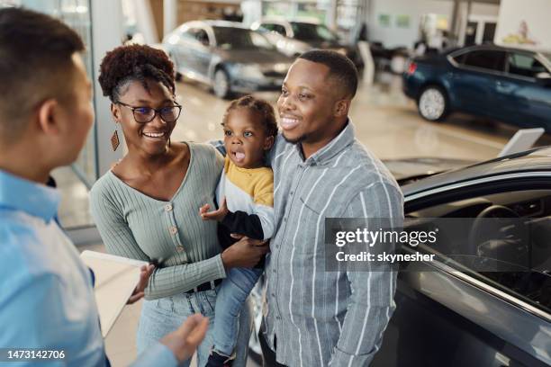 happy black family talking to car salesperson in a showroom. - buying a car 個照片及圖片檔