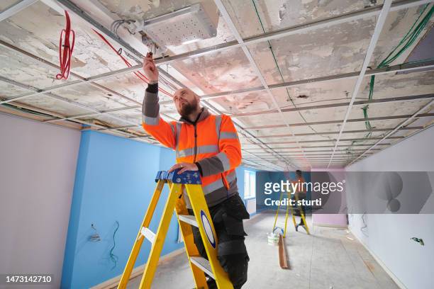electricians testing ceiling fixtures - building construction site stock pictures, royalty-free photos & images