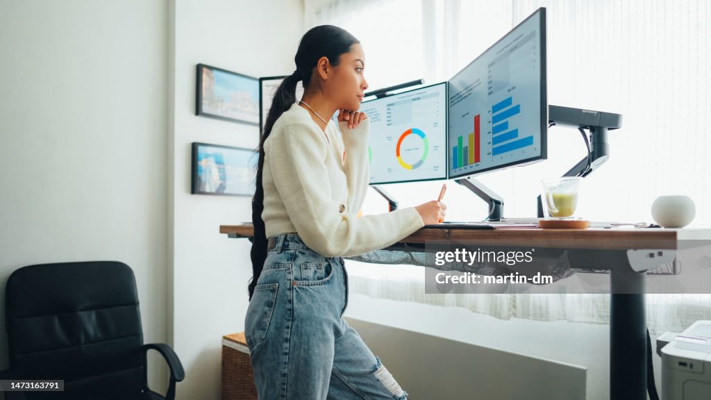 Frau mit Rückenschmerzen bei der Arbeit am Stehpult home office