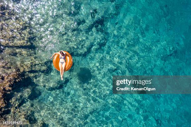 young woman lying on sea ring in the clear sea. - ölüdeniz stock pictures, royalty-free photos & images