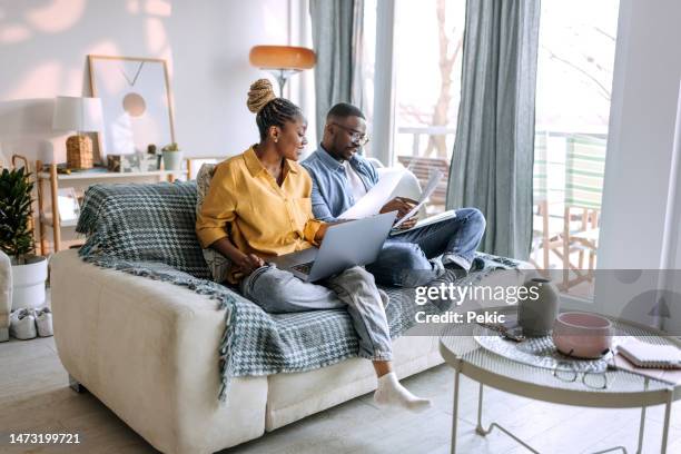young smiling couple working from home, going over paperwork - couple stockfoto's en -beelden