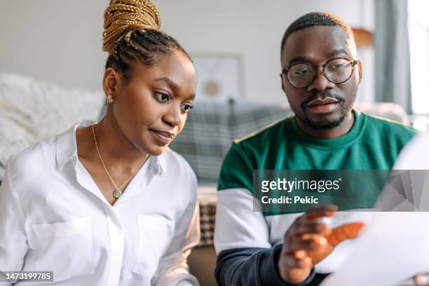 close up shot of young couple going over bills at their apartment - thinking for investment stock pictures, royalty-free photos & images